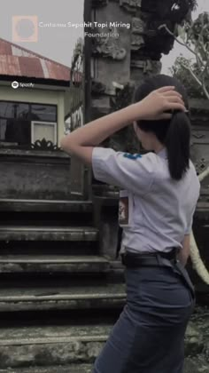 a woman standing in front of some steps with her hands on her head and looking down at the ground