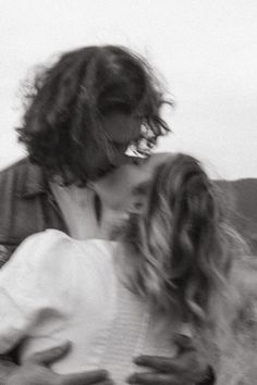 a man and woman kissing each other in front of a white background with blurry hair