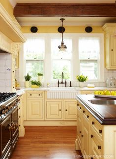 an image of a kitchen with yellow cabinets and white appliances on the counter top,