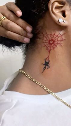 a woman with a spider web tattoo on her neck and behind her ear is a gold chain