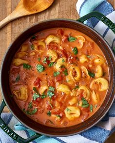 a pot filled with pasta and sauce on top of a wooden table