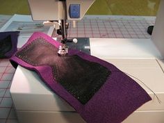 the sewing machine is working on the purple material that has been sewn into it