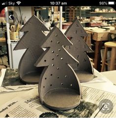 two paper mache christmas trees sitting on top of a piece of paper with holes in them