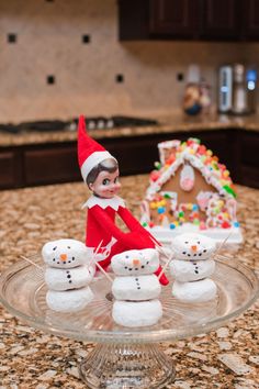 an elf sitting on top of a glass plate filled with snowmen