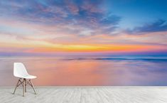 a white chair sitting on top of a wooden floor next to a large wall mural