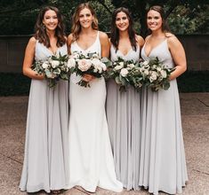 the bridesmaids are all wearing gray dresses and holding bouquets in their hands