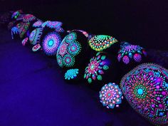 colorfully lit rocks are lined up on the ground in front of a black background