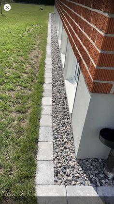 the side of a house with grass and rocks