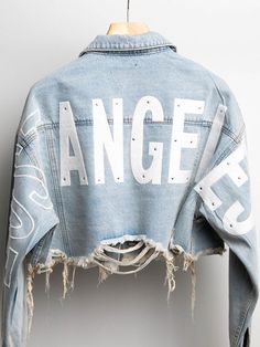 Cropped Distressed Denim Jacket FEATURES WIDE BACK PATCHES WITH THE LETTERS WORDING "LOST ANGELES" (LIGHT RHINESTONE ON LETTERS) DISTRESS HEMLINE, LONG SLEEVES, COLLAR, FRONT BUTTON DOWN AND CHEST POCKETS. PLEASE NOTE THAT ALL OF OUR PRODUCTS ARE HAND MADEFabric78% COTTON 15% RAYON 7% POLYESTER Model is wearing smallModel measurements, height and weight located in size chartAll models wear 4" heels in picturesOrder ships within 24-48 hours or sooner (Monday-Friday)78% Cotton15% Rayon 7% Polyeste Casual Beach Wear, Distressed Denim Jacket, Twin Peaks, Shop Swimwear, New Arrival Dress, Height And Weight, Monday Friday, Distressed Denim, Short Pants