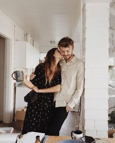 a man and woman standing next to each other in front of a kitchen counter top