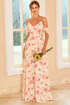 a woman standing in front of a window wearing a floral print dress and holding a flower bouquet