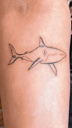 a shark tattoo on the right thigh is shown in black and grey ink, with an outline of a shark