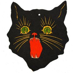 a black cat with green eyes and an orange hand painted on it's face