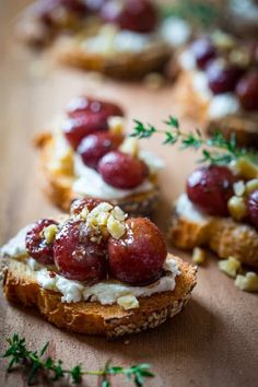 an open face sandwich topped with fruit and nuts on a wooden table next to other food items