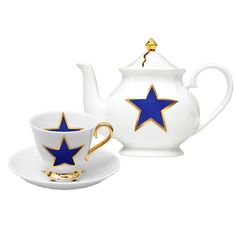 a white tea pot and saucer with blue stars on the side, sitting next to each other