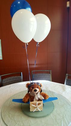 a teddy bear sitting on top of a table with two balloons in the shape of heart