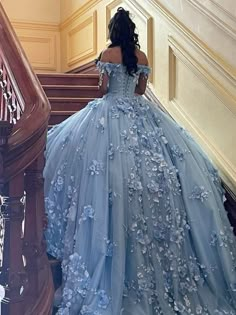 a woman in a blue dress walking down some stairs