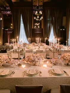 a dining room with tables and chairs covered in white linens, candles and flowers