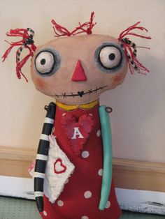 a stuffed animal with big eyes and a red dress holding a black object in it's hand