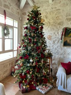 a decorated christmas tree in the corner of a living room with red and gold decorations