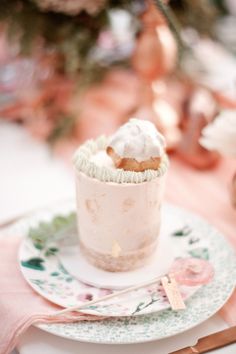 a cupcake sitting on top of a white plate next to a pink table cloth