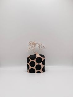 a black and white vase with a flower on top