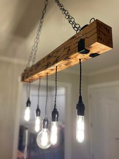 three light bulbs are hanging from a wooden beam with chains attached to the lightshades