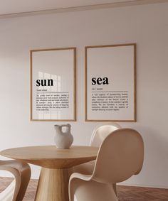 two framed pictures hang on the wall above a round table with chairs and a vase