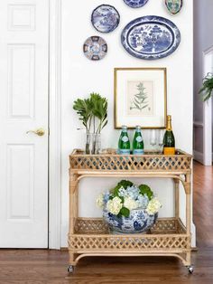 a table with plates and vases on it in front of a white door that is decorated with blue and white flowers