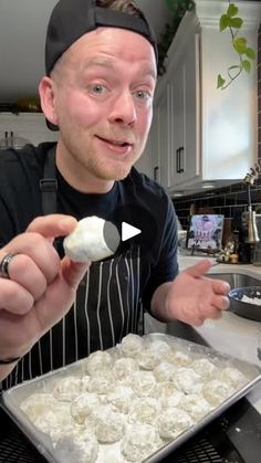 a man holding a spoon in his hand while cooking food on a stove top next to a sink