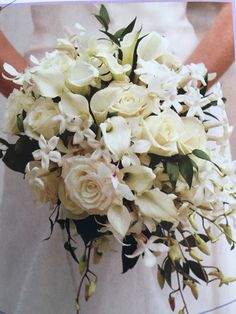 a bride's bouquet with white flowers and greenery is shown in this photograph