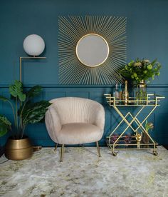 a living room with blue walls, gold accents and a chair in front of a mirror