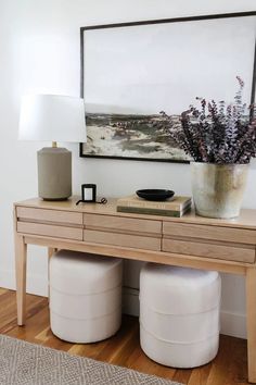 a wooden table with two white stools and a vase filled with flowers on top