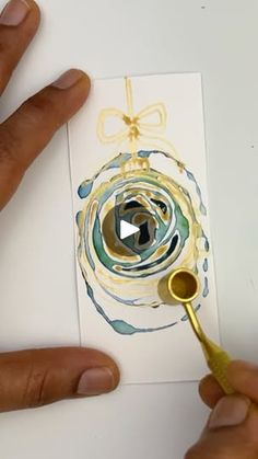 someone is painting an ornament on paper with gold paint and a golden brush