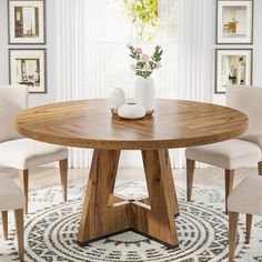 a round wooden table with chairs around it in a living room area next to pictures on the wall