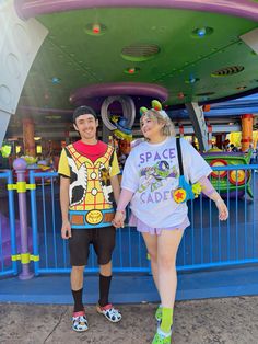 a man and woman standing next to each other in front of a colorful carnival ride