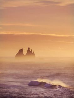 the sun is setting over some rocks in the ocean