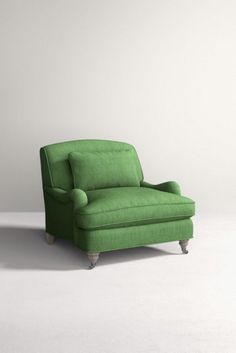 a green chair sitting on top of a white floor next to a lamp and wall