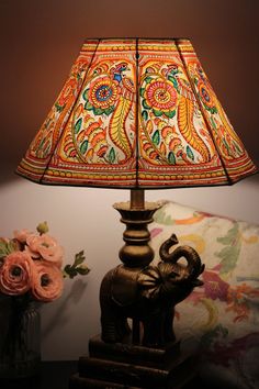 an elephant lamp is sitting on a table next to a vase with flowers and a flower arrangement