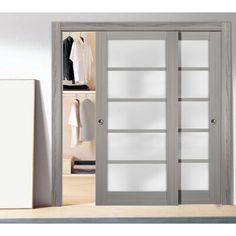 an open closet with white doors and clothes on hangers next to it in a room