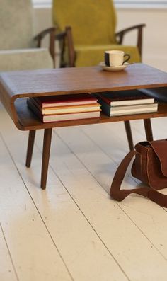 a coffee table with books and a cup on it in the middle of a room