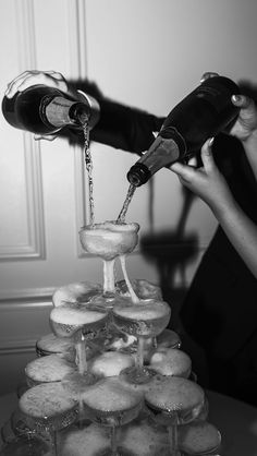 a woman pours champagne on top of a tower of doughnuts in black and white