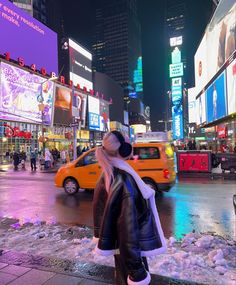 a woman standing on the side of a road in front of a taxi and neon signs