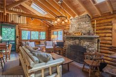 a living room filled with furniture and a fire place in the middle of a wooden building