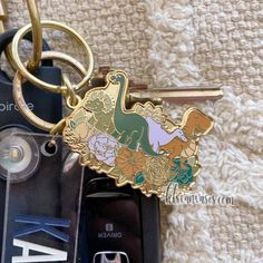 a cell phone keychain with an image of a dinosaur and flowers on it