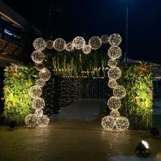 an archway decorated with balls and lights in the middle of a walkway at night time