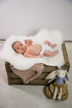 a baby laying on top of a wooden crate next to a stuffed animal and toy rabbit