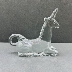 a glass figurine of a unicorn sitting on the ground