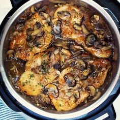 a pot filled with chicken and mushrooms on top of a table next to a blue towel