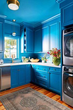 a kitchen with blue painted walls and wooden flooring, stainless steel appliances and dishwasher